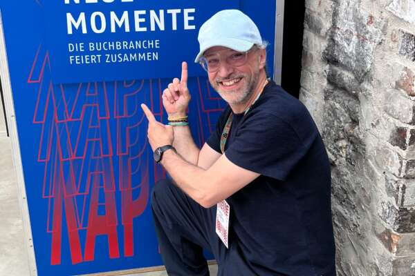 Ein Mann hockt vor einem Plakat mit der Aufschrift "Neue Kapitel, Neue Momente".