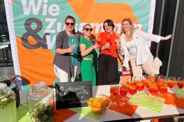Vier Frauen freuen sich hinter einem Tisch voller vorbereiteter Aperol Spritz auf den Begin des Hoffest.