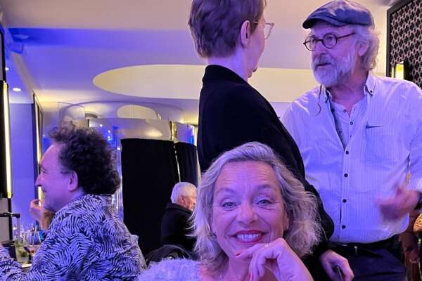 Sonja Oberndorfer sitzt am Abend in der Hotelbar umgeben von bekannten Autoren, links Bernhard Hennen und rechts Klaus-Peter Wolf.