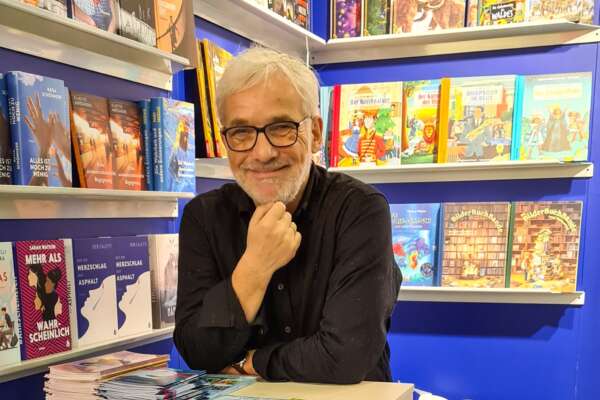 Vertreter Michael Boehme steht mit Stehtisch in einer Bücherei.