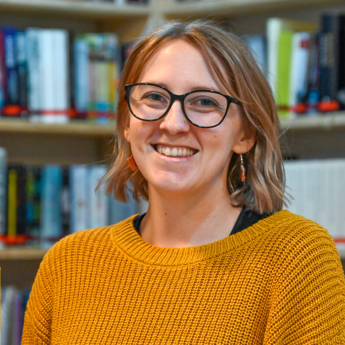 Porträt von Irina Bluemel Kolck vor einem Bücherregal in Ihrer Buchhandlung die Erlesene.