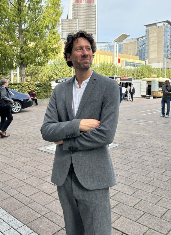 David Mesche mit einem schmunzeln und verschränkten Armen auf dem Gelände der Frankfurter Buchmesse.