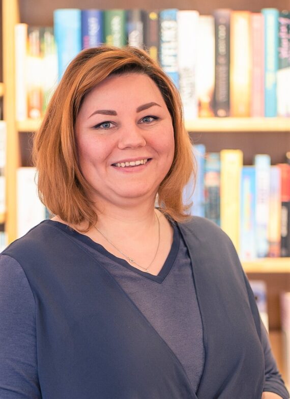 Porträt von Hanna Maschke vor einem Bücherregal in einer Buchhandlung.