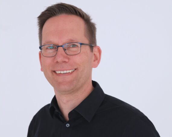 Porträt von Marc Janeczek vor einer weißen Wand.