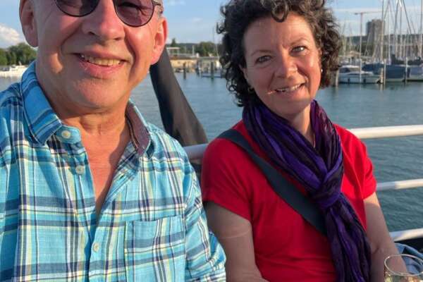 Barbara Bacher-Zink und Irimbert Kastl sitzen auf einer Bank am Ufer eines Hafens.