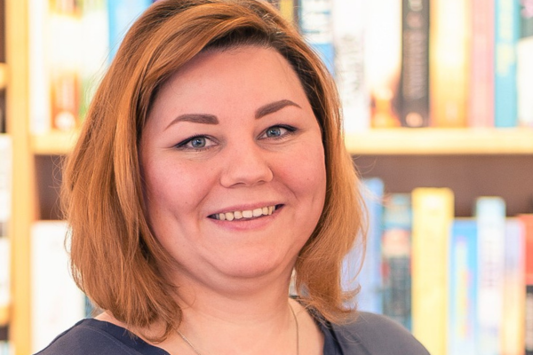 Porträt von Hanna Maschke vor einem Bücherregal in einer Buchhandlung.