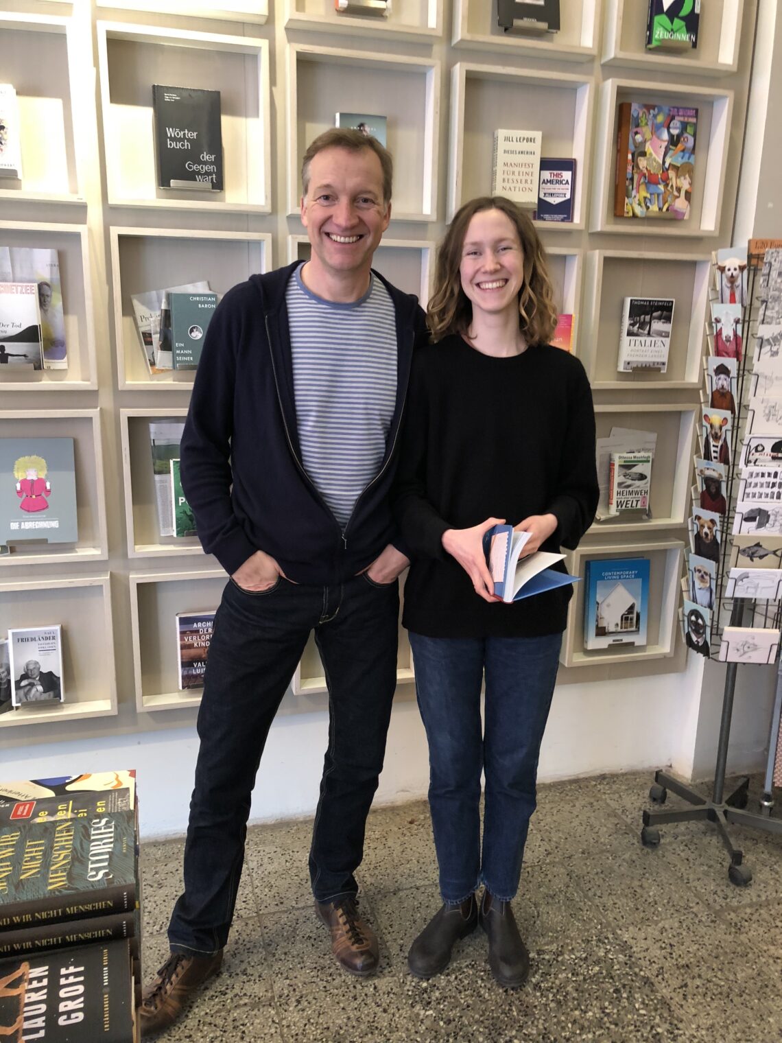 Ein Mann und eine Frau stehen vor einer Wand wo Bücher in Bilderrahmen präsentiert werden.
