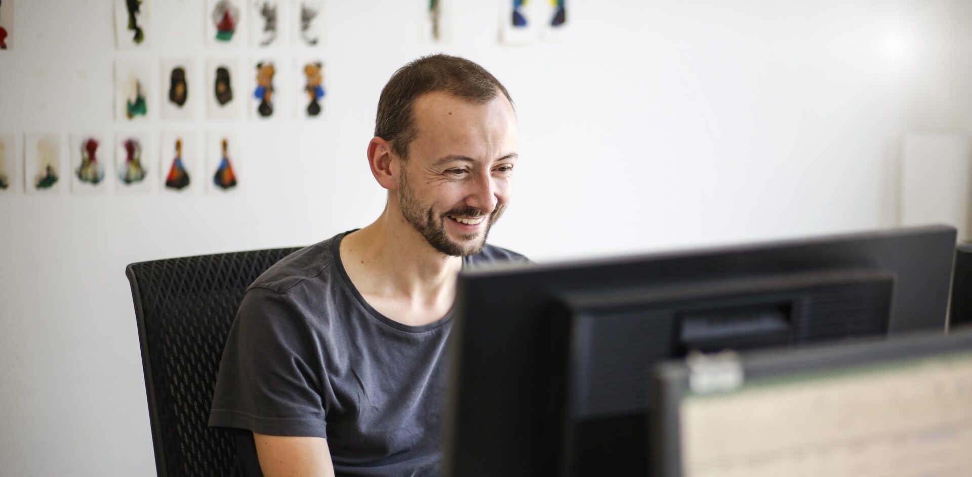 Ein Mann sitzt in einem Büro am Schreibtisch und arbeitet am Computer.