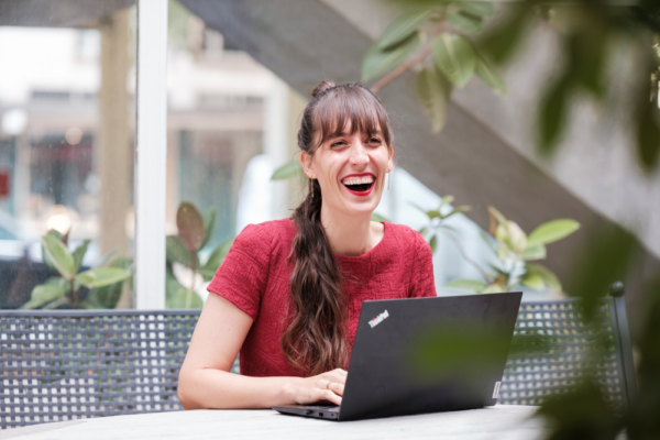 Vertriebskollegin lacht herzlich am Laptop.