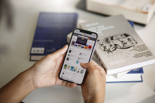Zwei Hände halten ein Smartphone auf dem die Webseite von VLB-TIX aufgerufen ist.
