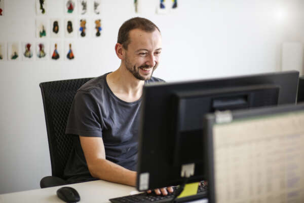 Ein Mann sitzt in einem Büro am Schreibtisch und arbeitet am Computer.