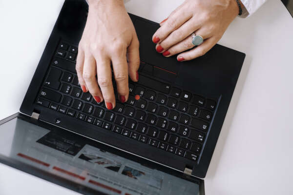 Zwei Hände liegen auf der Tastatur eines Laptops.